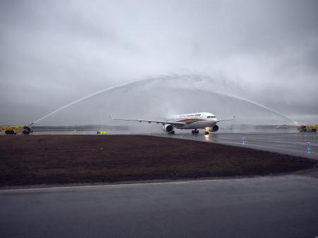 Airplane is receiving a water salute on a cloudy day.