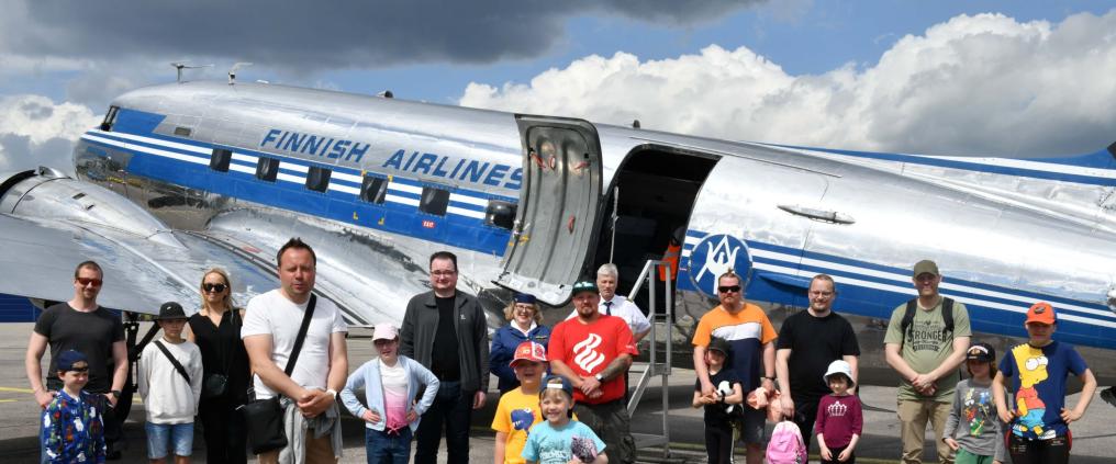Lapsia ja aikuisia vanhan DC3-koneen edessä